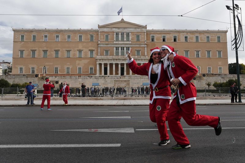 © Reuters. People dressed in Santa costumes run past the Greek parliament as they take part in the Santa Claus Run in Athens