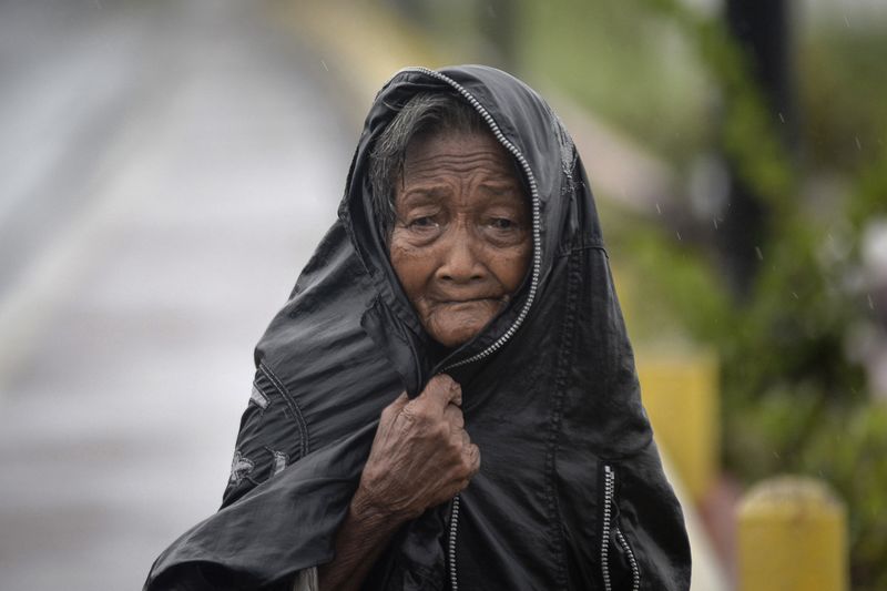 © Reuters. An elderly woman shields herself from the rain brought by Typhoon Hagupit in Noveleta town, Cavite province, south of Manila