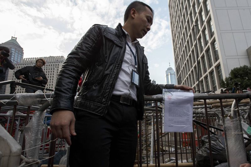 © Reuters. Oficial coloca notificação em barricada de acampamento de manifestantes em Hong Kong