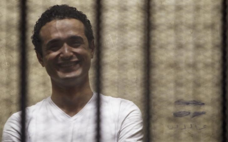© Reuters. Egyptian activist Ahmed Douma smiles from behind bars during his trial at the New Cairo court, on the outskirts of Cairo