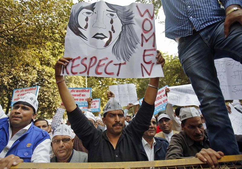 © Reuters. Supporters of AAP hold placards and shout slogans behind a police barricade during a protest against the rape of a female taxi passenger in New Delhi