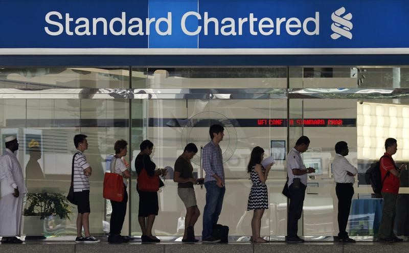© Reuters. People queue up outside a Standard Chartered Bank branch before operation hours at the central business district in Singapore