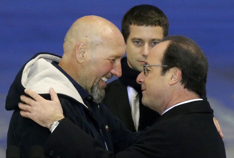 © Reuters. Presidente francês, François Hollande, e o ex-refém Serge Lazaveric se abraçam no aeroporto militar de Villacoublay, nos arredores de Paris