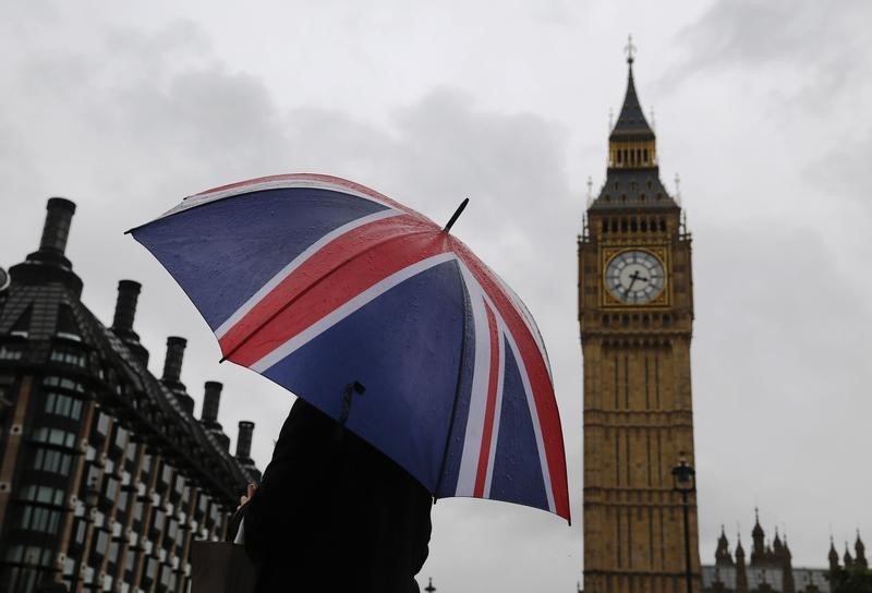 © Reuters. A woman holds a Union flag umbrella in front of the Big Ben clock tower and the Houses of Parliament in London