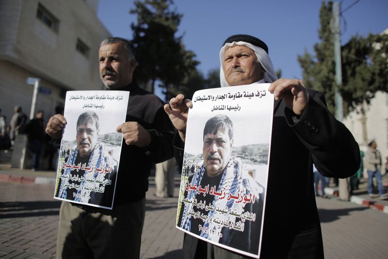 © Reuters. People hold posters of Palestinian minister Ziad Abu Ein at a hospital in the West Bank city of Ramallah