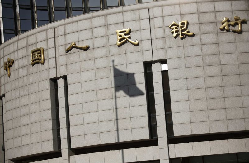 © Reuters. Fluttering Chinese national flag casts its shadow on the headquarters of the People's Bank of China, China's central bank, in central Beijing