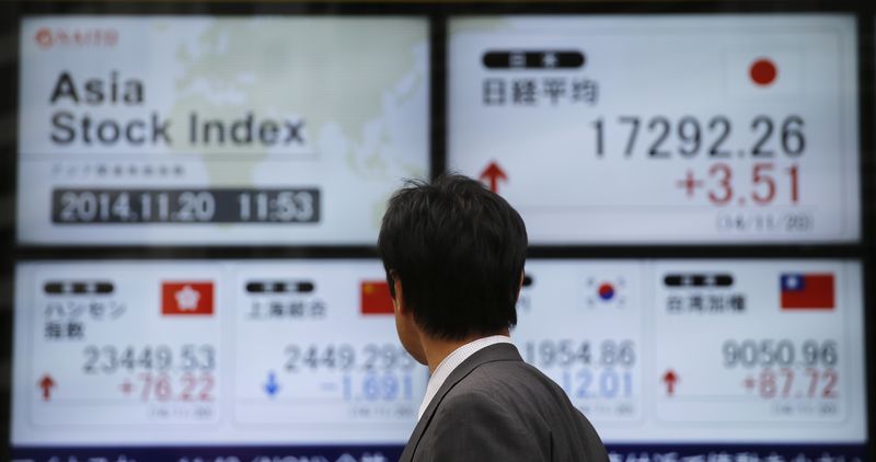 © Reuters. A man looks at electronic boards showing Asian stock indexes, outside a brokerage in Tokyo
