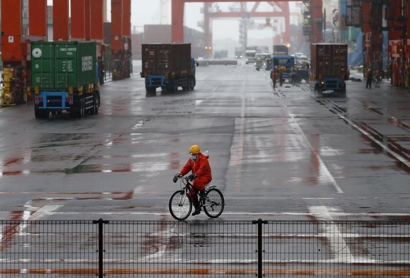 © Reuters. A worker rides a bicycle in a container area at a port in Tokyo