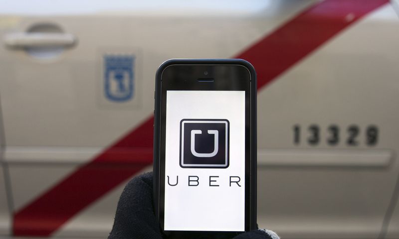 © Reuters. Photo illustration of logo of car-sharing service app Uber on a smartphone in front of a taxi in Madrid