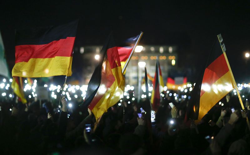 © Reuters. Participants hold up their mobile phones and wave German national flags during a demonstration called by anti-immigration group PEGIDA in Dresden