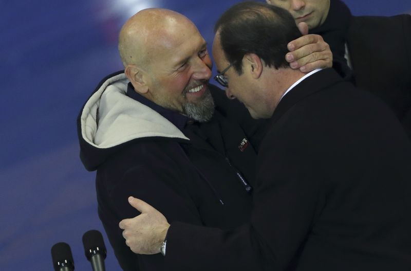 © Reuters. French President Francois Hollande and former hostage Serge Lazarevic hug each other after delivering speeches at the Villacoublay military airport, near Paris