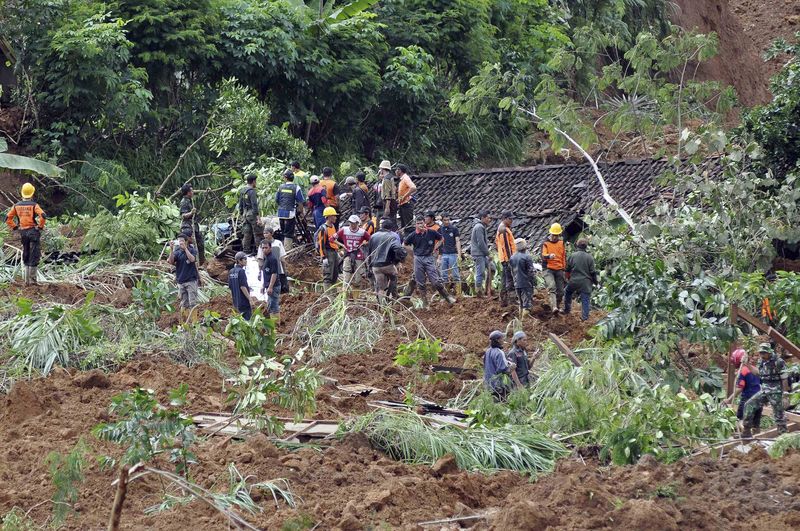 © Reuters. Rescue workers stand near houses buried in the mud after a landslide hit the village of Sampang in Banjarnegara