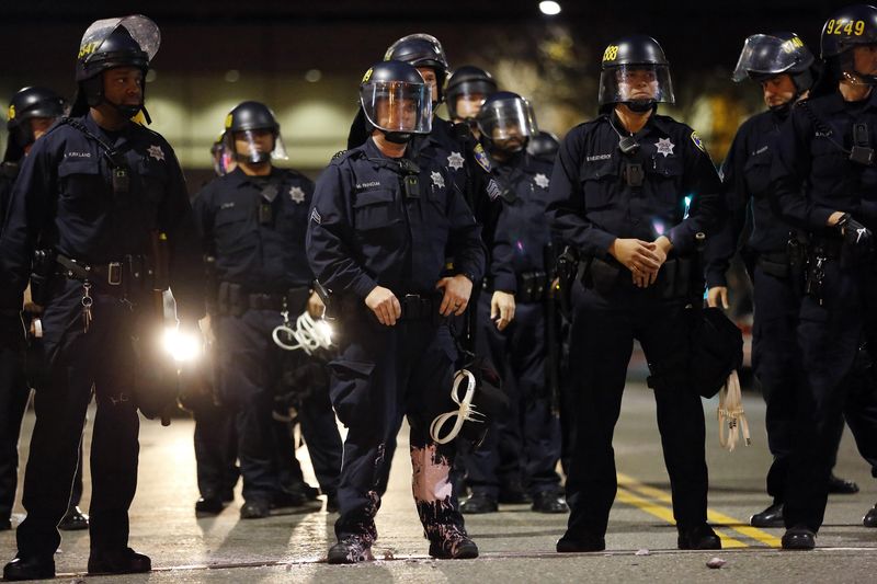 © Reuters. A police officer looks into the crowd, after he was hit on the leg with paint thrown by protesters, in Oakland