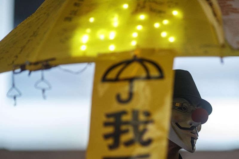 © Reuters. A pro-democracy protester wears Guy Fawkes mask as he holds up yellow umbrella,  symbol of Occupy Central civil movement at area occupied by protesters at Causeway Bay in Hong Kong