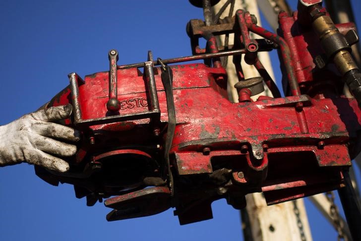 © Reuters. A man works on the rig of an oil drilling pump site in McKenzie County outside of Williston