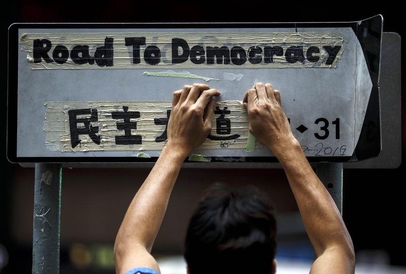 © Reuters. A worker removes masking tape left on road sign by pro-democracy protesters during clearance at last "Occupy" protest site blocking main road at Causeway Bay shopping district in Hong Kong