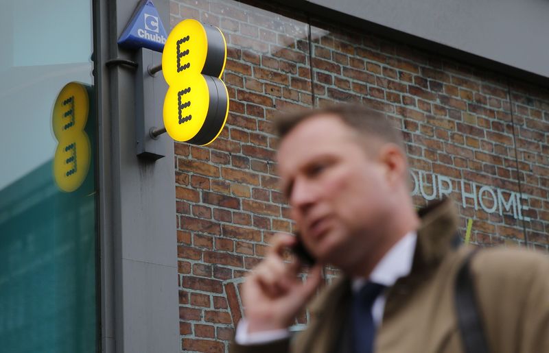 © Reuters. File photograph shows a pedestrian talking on the phone as he walks past an EE shop on Oxford Street in London
