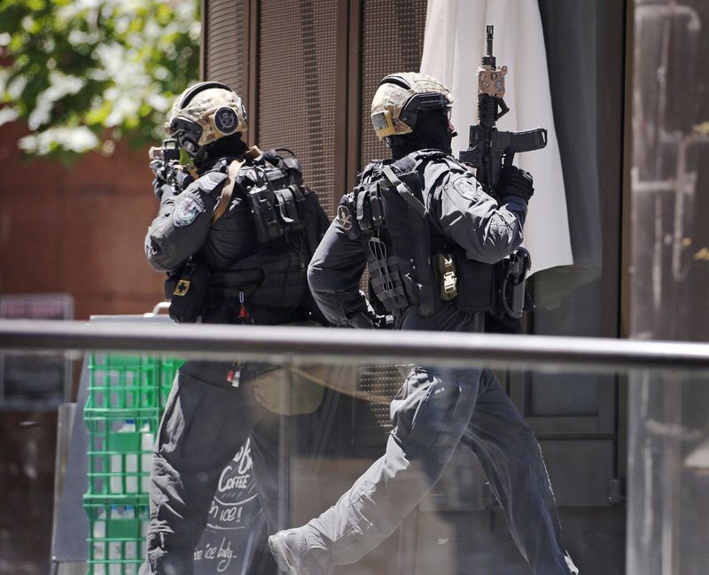 © Reuters. Un policía corre en Martin Place, cerca del café Lindt, donde un grupo de rehenes está siendo retenido