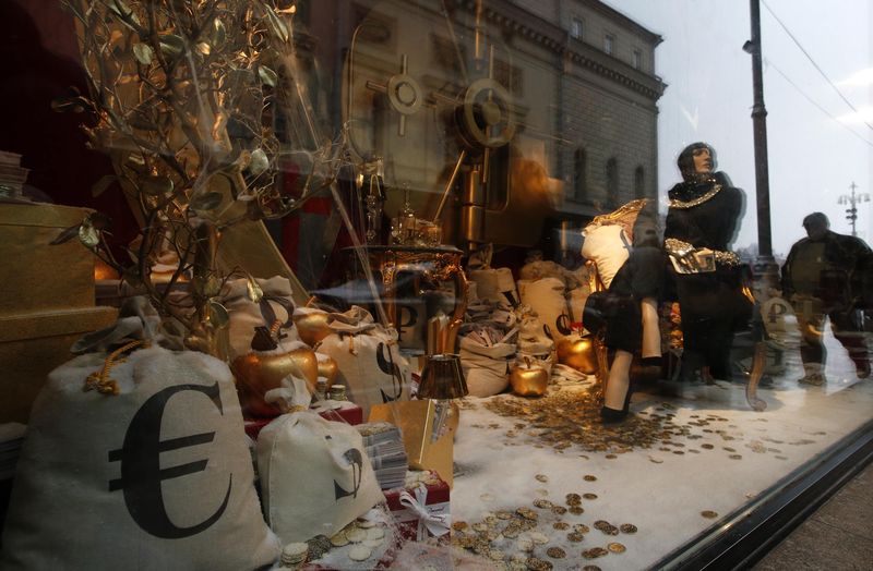 © Reuters. People are reflected in a shop window, with logos of Euro, U.S. dollar and Rouble seen on bags inside, in central Moscow