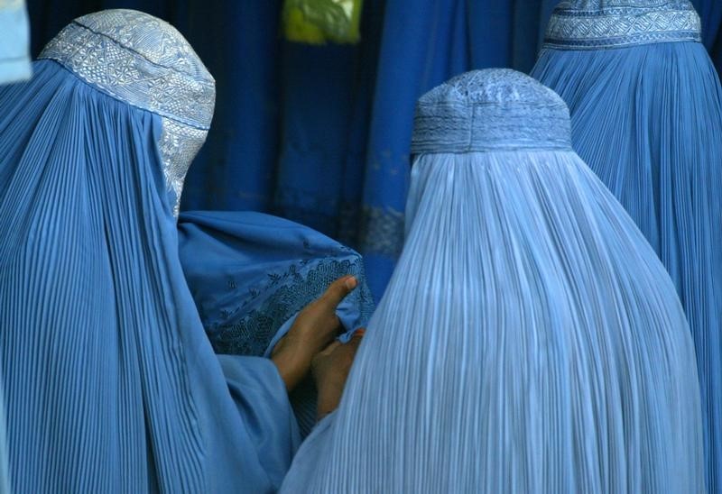 © Reuters. Afghan women purchase burqas at a roadside shop in Kabul