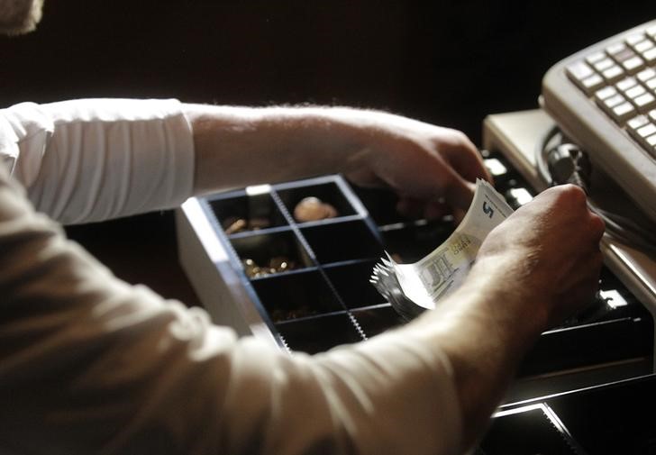 © Reuters. Bar manager Krists Pumpitis loads a cash register with euro coins and banknotes in Riga