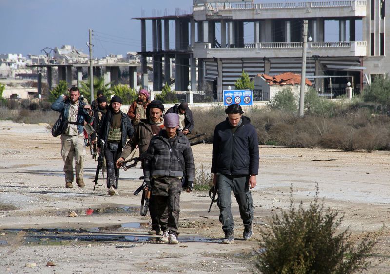 © Reuters. Combatentes rebeldes caminham em torno da base al-Hamidyeh, na província de Idlib, na Síria 