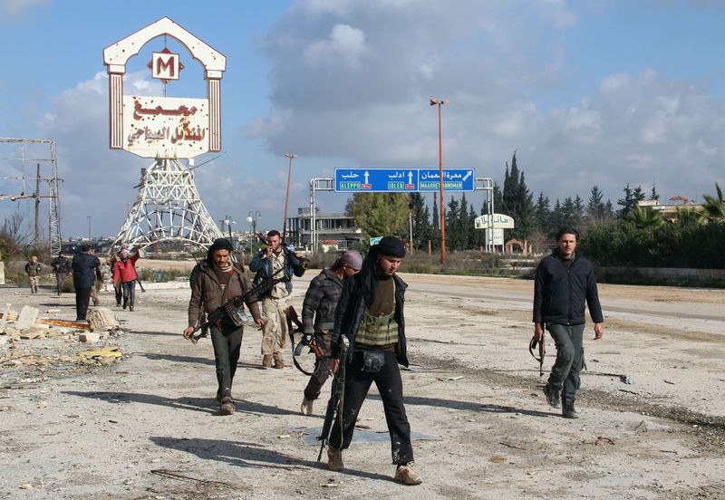 © Reuters. Rebel fighters walk around al-Hamidiyeh base, one of two military posts they took control of from forces loyal to Syria's President Bashar al-Assad in the northwestern province of Idlib
