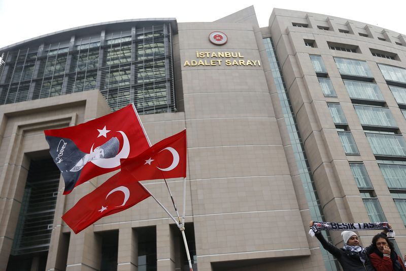 © Reuters. Protesters, who are supporting soccer fans on trial, stand near Turkish flags bearing an image of the founder of modern Turkey, Ataturk outside a court in Istanbul