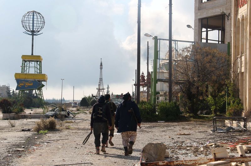 © Reuters. Combatentes rebeldes caminham no arredores da base al-Hamidiyeh, na província de Idlib, Síria