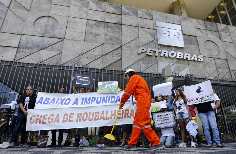 © Reuters. Manifestante varre a entrada da sede da Petrobras durante protesto contra corrupção