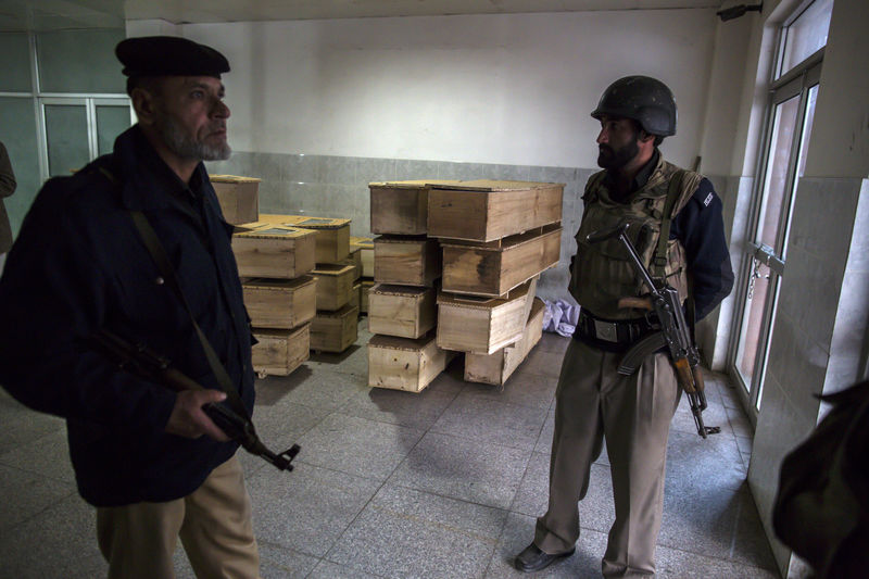 © Reuters. Policemen stand beside empty coffins at the hospital after an attack by Taliban gunmen on the Army Public School in Peshawar