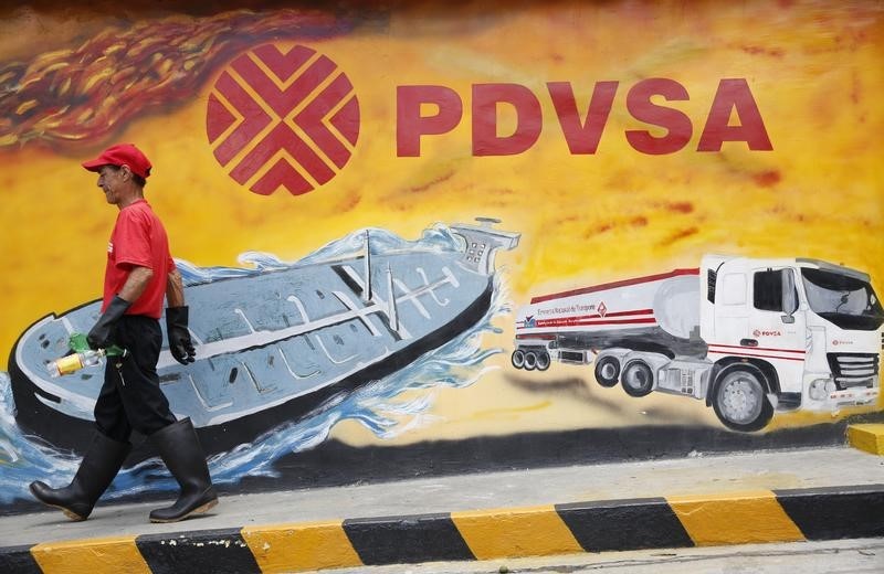 © Reuters. A worker walks past a mural with a PDVSA logo at its gas station in Caracas
