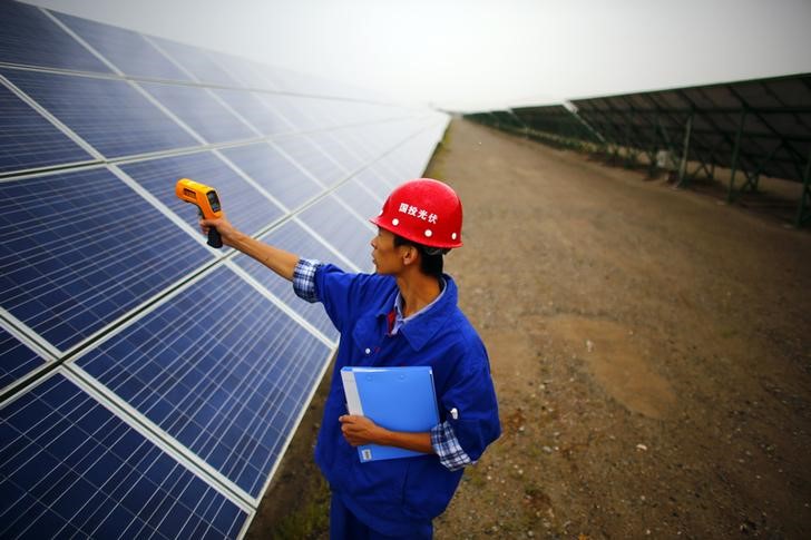 © Reuters. A worker inspects solar panels at a solar farm in Dunhuang