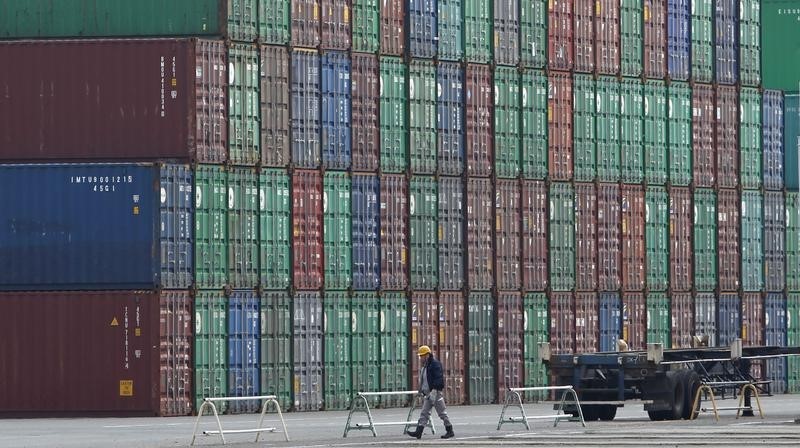 © Reuters. A worker walks next to containers at a port in Tokyo