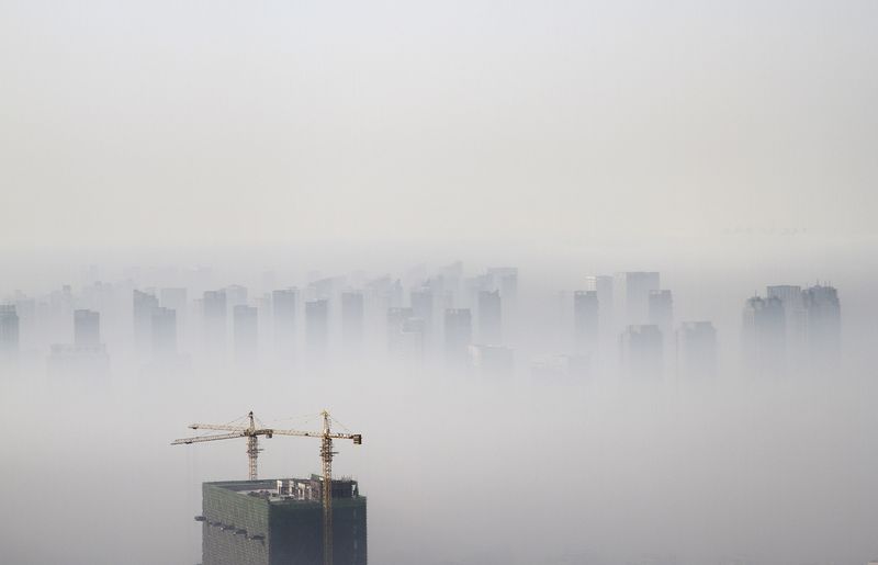 © Reuters. File photo of a building under construction amidst smog on a polluted day in Shenyang
