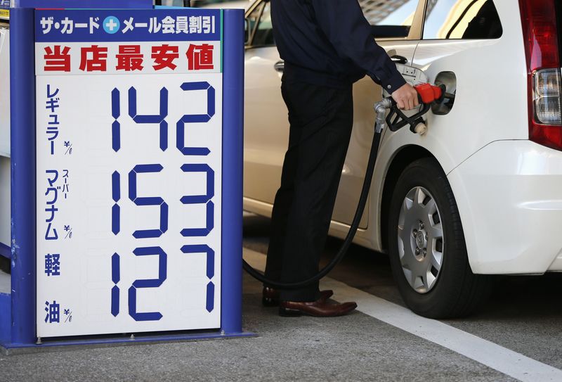 © Reuters. An man refuels a vehicle next to a pricing quotation board at a petrol station in Tokyo