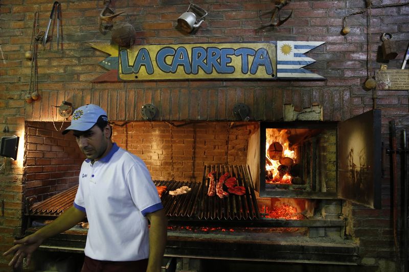 © Reuters. Hugo Bautista, barbecues meat at the Uruguayan Center in Caracas