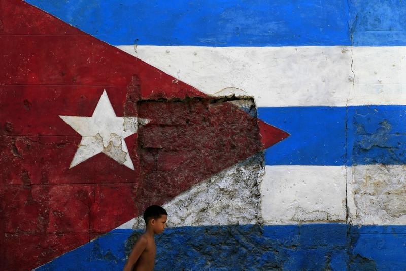 © Reuters. Мальчик проходит мимо выкрашенной в цвета кубинского флага стены в Гаване