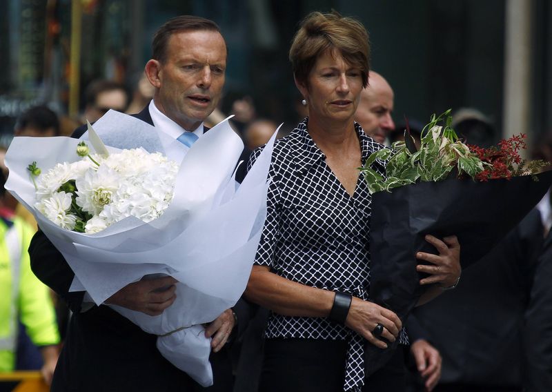 © Reuters. Australian Prime Minister Tony Abbott and his wife Margie prepare to place floral tributes  near the cafe in central Sydney where hostages were held for over 16-hours