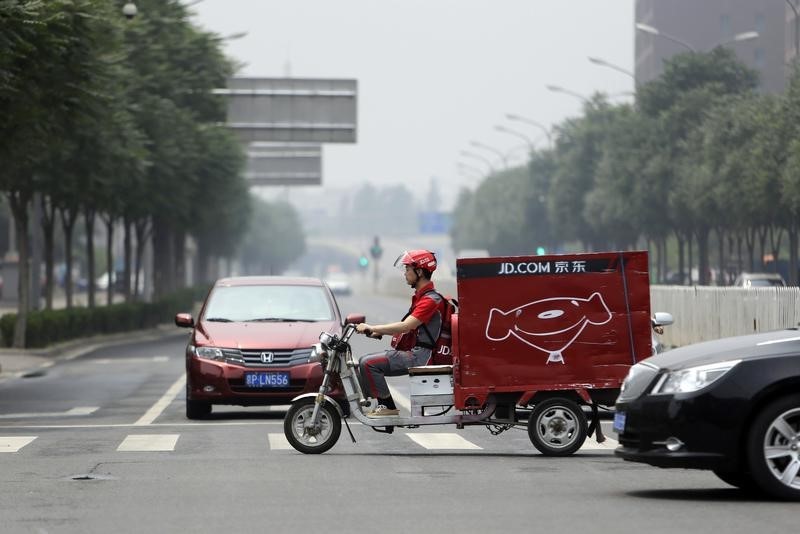 © Reuters. Liu, CEO and founder of China's e-commerce company JD.com, crosses a street on an electric tricycle during a delivery run in Beijing