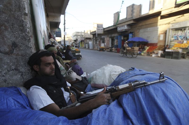 © Reuters. A Shi'ite Houthi fighter sits behind sandbags near a checkpoint in Sanaa