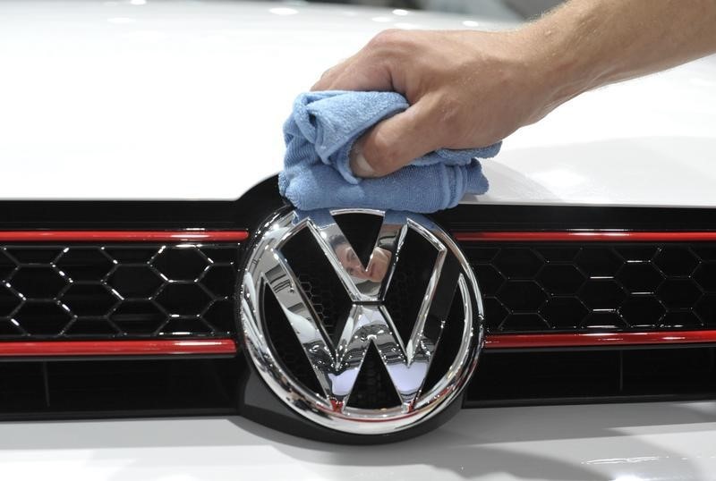 © Reuters. A man polishes the Volkswagen logo on a vehicle of an exhibition which is part of the annual shareholders meeting of Volkswagen AG in Hamburg