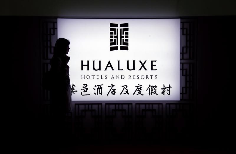 © Reuters. A woman stands near an illuminated sign for InterContinental Hotels Group's new hotel brand called Hualuxe Hotels and Resorts, during its official launch inside the Forbidden City in Beijing