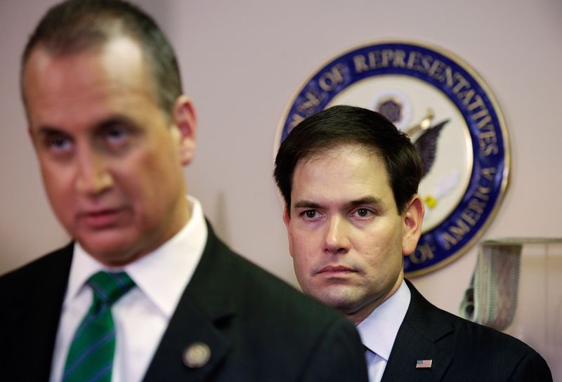 © Reuters. Senator Marco Rubio, (R-FL) listens to Rep. Mario Diaz-Balart, (R-FL),  during a press conference in Miami