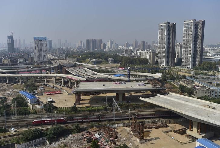 © Reuters. An overpass is seen under construction as a train travels past in Wuhan