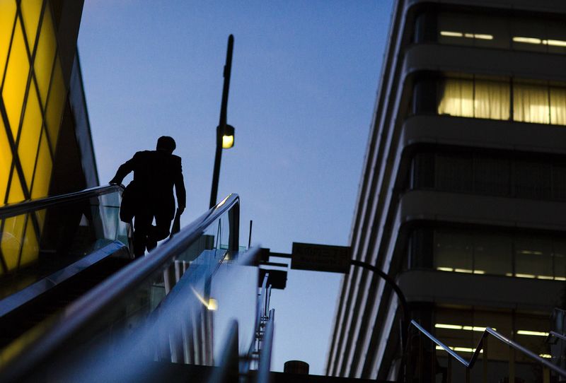 © Reuters. Businessman rides an escalator at a banking district in central Tokyo