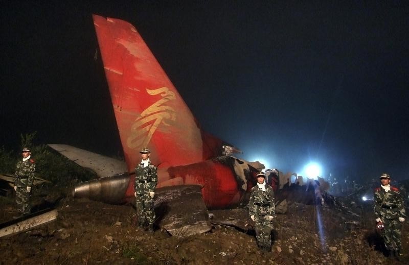 © Reuters. Paramilitary policemen stand next to the wreckage of a crashed passenger plane in Yichun