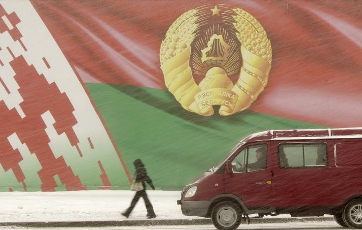 © Reuters. Люди у изображения белорусского флага и герба в центре Минска