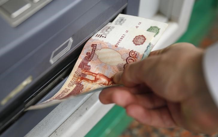 © Reuters. Man uses a cash dispenser to receive roubles in central Moscow