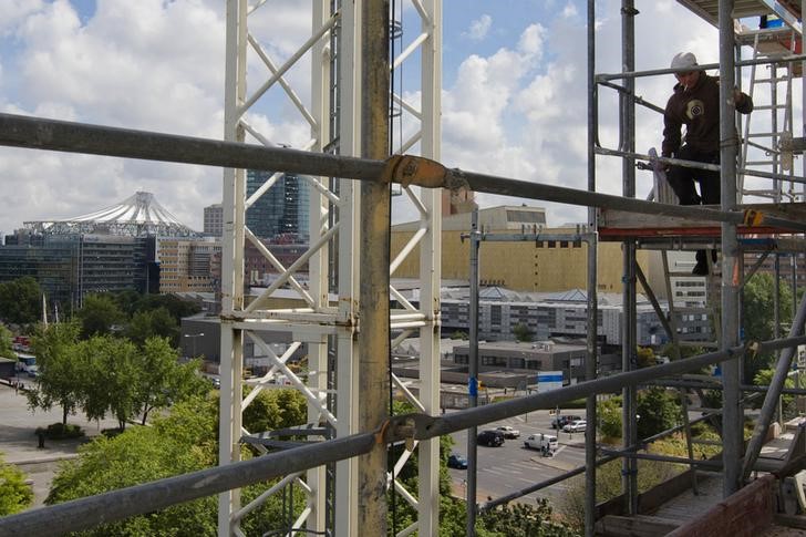 © Reuters. Worker climbs down scaffolding at construction site near Potsdamer Platz in Berlin